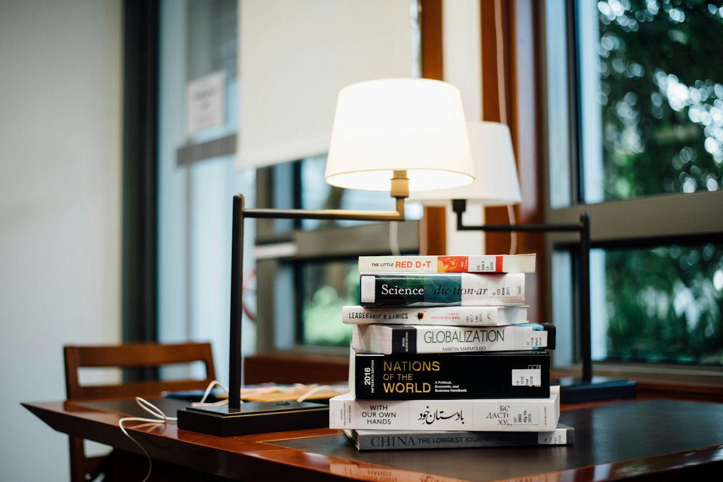Libri accademici impilati su una scrivania di legno lucido.